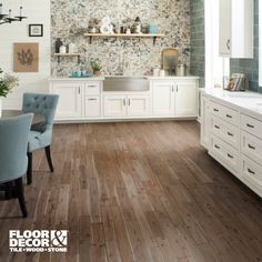 a kitchen with wood floors and white cabinets, blue chairs and a sink in the center