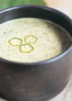 a black bowl filled with broccoli soup on top of a cloth covered table