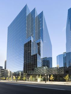 two very tall buildings sitting next to each other on the side of a road with trees in front of them