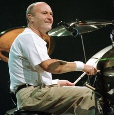 a man sitting in front of a drum kit on stage with his hands behind the drumsticks