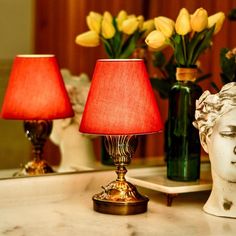 two lamps are sitting on a table next to vases with tulips in them