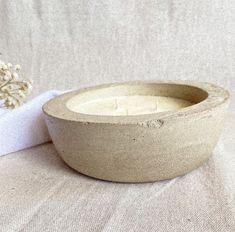 a white bowl sitting on top of a table next to a flower