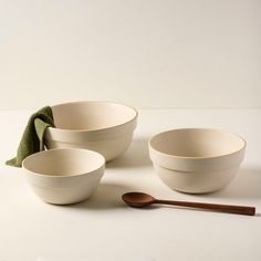 three white bowls with wooden spoons next to each other