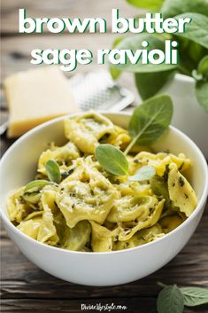 a white bowl filled with pasta and spinach sauce on top of a wooden table