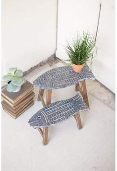 two fish shaped tables sitting next to each other on top of a white floor covered in books