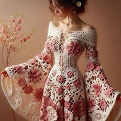 a woman in a crochet dress with flowers on her shoulders and arms, standing next to a flower vase