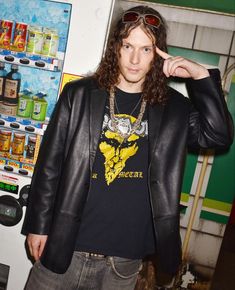 a young man in a black jacket and sunglasses standing next to a vending machine