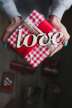 a woman holding a red and white present box with the word voce on it