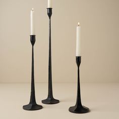 three black candlesticks with one white candle