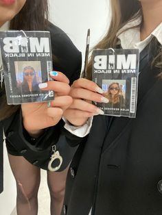 two women holding up their id cards with the same person on them as they stand next to each other