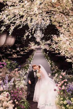 a bride and groom kissing in the middle of an aisle with flowers all around them