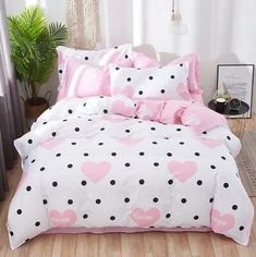 a bed covered in pink and black polka dots with hearts on the comforter, next to a potted plant