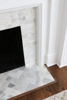 a fireplace with white marble and wood flooring