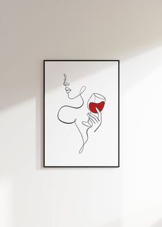 a white wall with a black frame holding a drawing of a woman and a glass of red wine