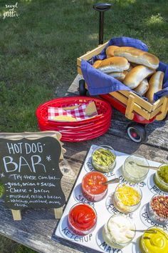 hot dog bar with buns and condiments on a picnic table