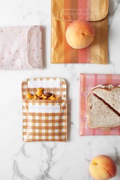 three pieces of bread and two peaches on a marble counter top with paper bags