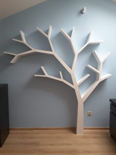 a white tree is in the corner of a room with blue walls and wooden floors