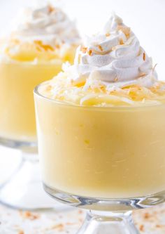 two small desserts with whipped cream and orange zest on the top are sitting in glass dishes