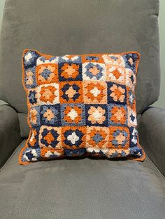 an orange and blue pillow sitting on top of a gray couch