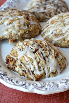 four cookies on a plate with icing drizzled over them and sitting on a table