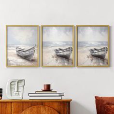 three framed pictures hanging on the wall above a dresser with a vase and coffee cup