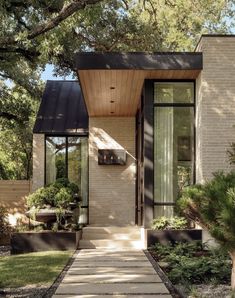 a small house with a walkway leading to the front door and side entrance that is surrounded by trees