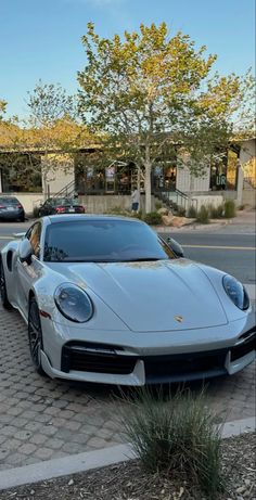 a white sports car parked on the side of the road in front of a building