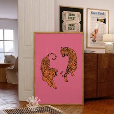 a pink poster with two tigers on it in front of a dresser and other items