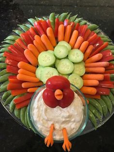 a platter with carrots, celery, cucumbers and dip