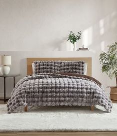 a bed in a bedroom with a gray comforter and pillows on top of it