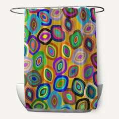 a colorful shower curtain with circles and dots in multicolors on the outside, hanging from a metal rod