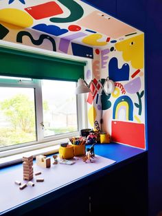 a child's room with colorful wallpaper and toys on the window sill