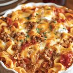 a casserole dish with meat, cheese and sauce in it on a table