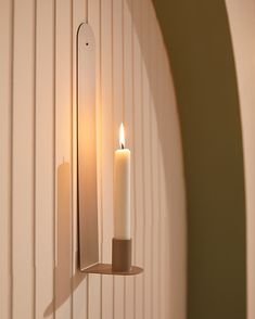 a candle is lit on the wall next to a mirror