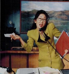 a woman in a yellow suit is talking on the phone and holding her hands out