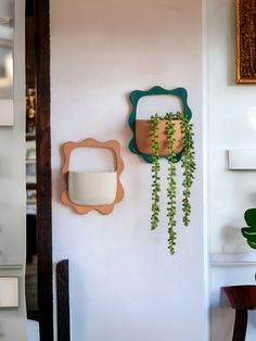 there is a plant hanging on the wall next to a mirror and potted plant