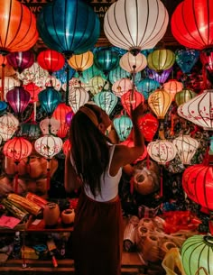 a woman standing in front of many colorful lanterns