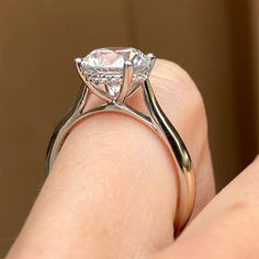 a close up of a person's hand holding a ring with a diamond on it