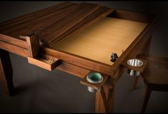 a wooden desk with two cups on it and one drawer open to show the contents