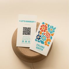 two business cards sitting on top of a wooden bowl next to a qr code