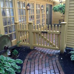 a brick walkway leading to a yellow house