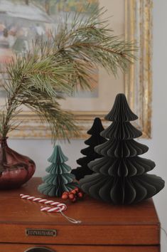 three small christmas trees on top of a wooden dresser next to a pine tree and candy canes