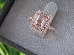 a fancy ring with an emerald cut diamond surrounded by pave diamonds on a cushion