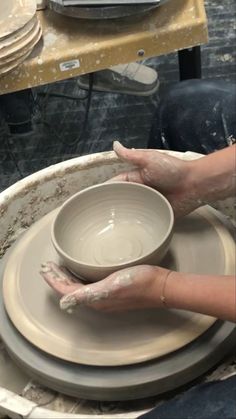 a person is making a bowl on a potter's wheel with their hands in it