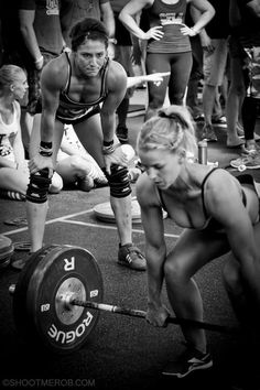 a group of people standing around each other in front of a barbell