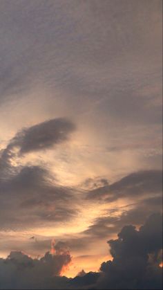 an airplane is flying high in the sky at sunset with clouds and sun behind it