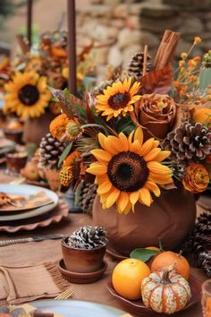 the table is set with sunflowers, pine cones and other autumn decor items