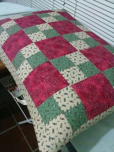 a red and green quilt sitting on top of a bed