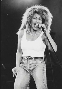 a black and white photo of a woman singing on stage with a microphone in her hand