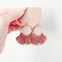 a pair of pink tasselled earrings on top of a card